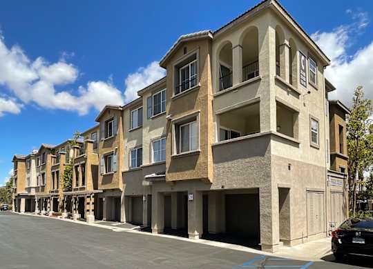 A row of apartment buildings with a car parked in front.