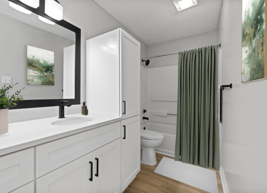 a bathroom with white cabinets and a green shower curtain