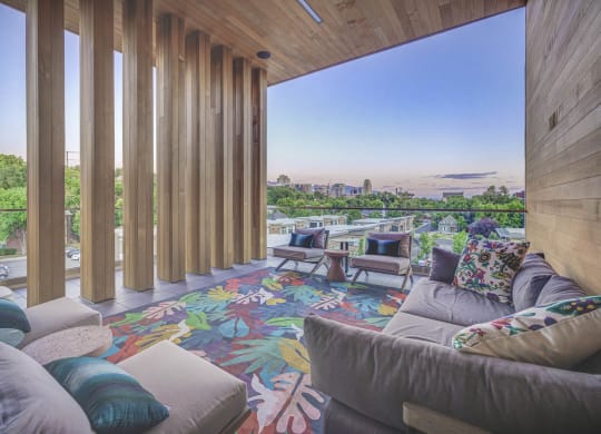 a living room with couches and chairs and a colorful rug with a view of the city