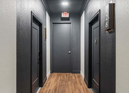 A hallway with doors on both sides and a sign above the middle door.