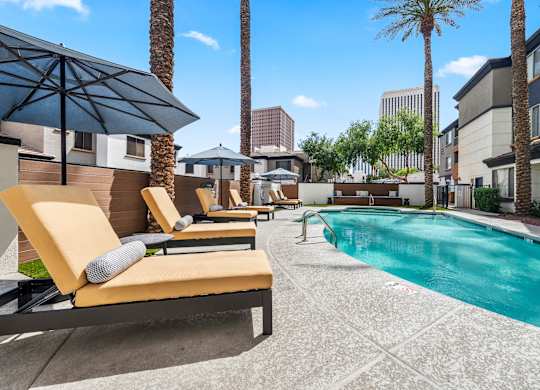 A pool area with sun loungers and palm trees.