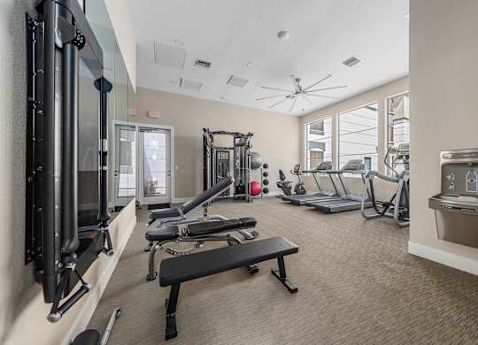 A gym with a variety of equipment including a treadmill, weights, and a bench.