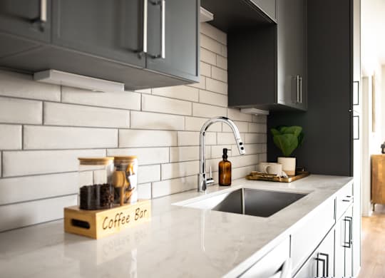 A kitchen with a marble countertop and a coffee bar.