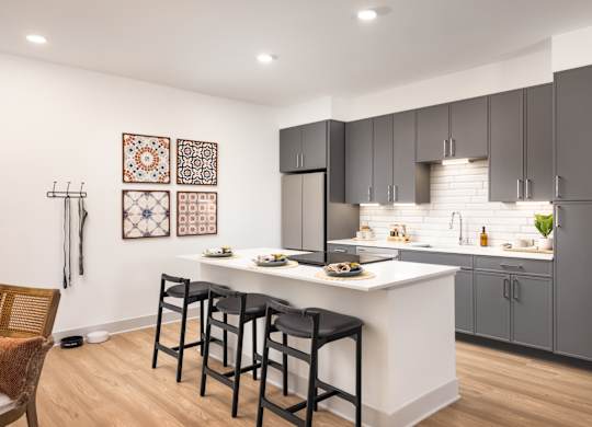 A kitchen with a white counter and black bar stools.