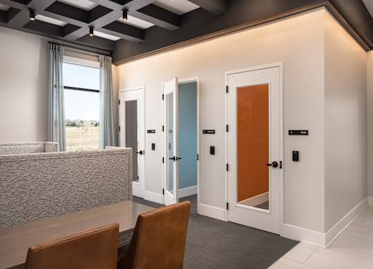 A room with a table and chairs and four doors.