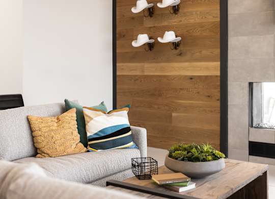 A grey couch with a bowl of plants on a coffee table in front of a wooden wall.