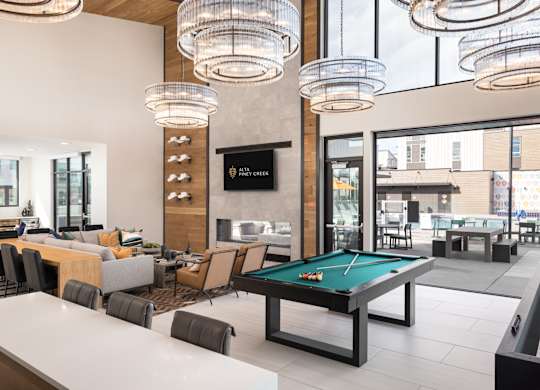A billiards table is in the middle of a room with a bar and a television.