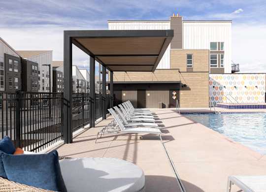 A pool area with lounge chairs and a table.