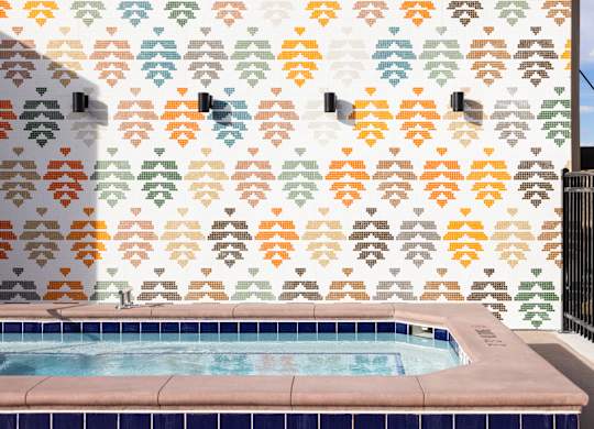 A pool with a wall that has a pattern of leaves on it.