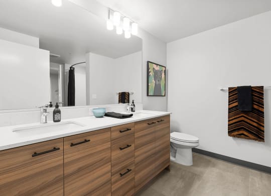 a bathroom with white walls and a wooden vanity with two sinks and a toilet at Ion Town Center, Shoreline, WA 98133