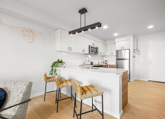a kitchen with white cabinetry and a large white island with a white countertop and yellow at Ion Town Center, Shoreline Washington