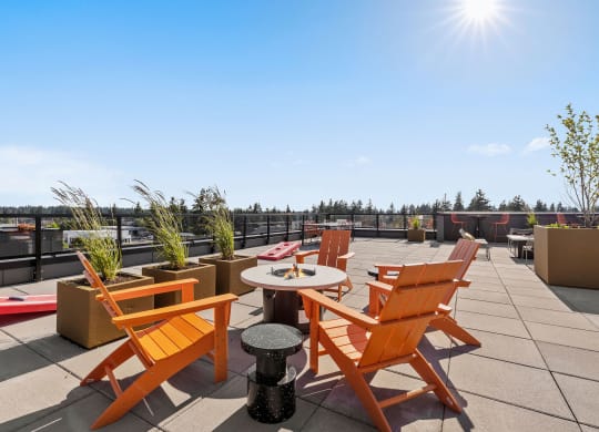 a rooftop terrace with orange chairs and a table with a pizza box on it at Ion Town Center, Shoreline, 98133