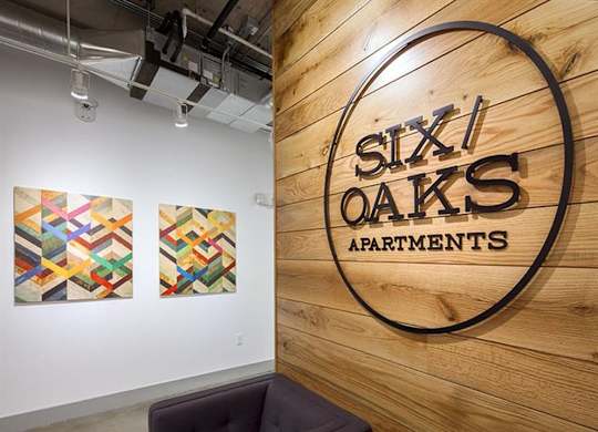 Property entrance sign on wood accent wall at Six Oaks Apartments, Bothell, Washington