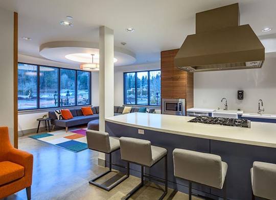 Community lounge with kitchen island and seating area at Six Oaks Apartments, Washington