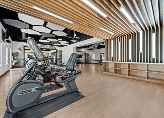 a spacious fitness center with hardwood floors and white walls
