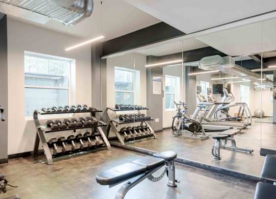 A gym with a variety of equipment including treadmills, weights, and exercise machines.