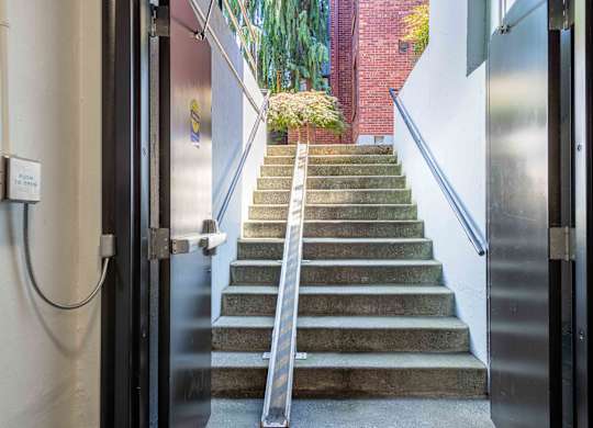 A set of stairs with a metal handrail leading to a door.