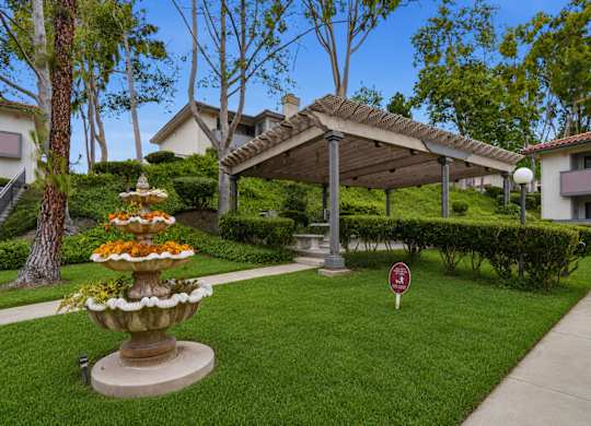 A garden with a fountain and a sign in front of a house.