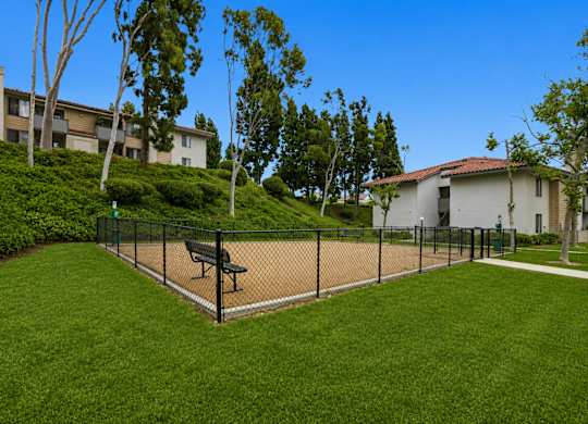 A park with a bench and a fence.