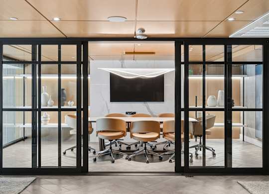 A conference room with a table and chairs is visible through a glass door.