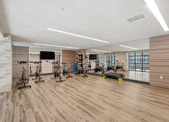 A gym with wooden floors and a variety of exercise equipment.