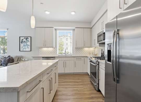 A modern kitchen with a stainless steel refrigerator and wooden floors.