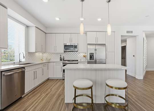 A kitchen with a bar stool in front of the island.