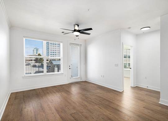 A room with a ceiling fan and a window overlooking a cityscape.
