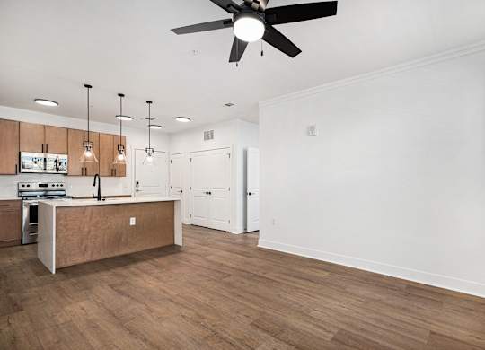A kitchen with wooden floors and a ceiling fan.