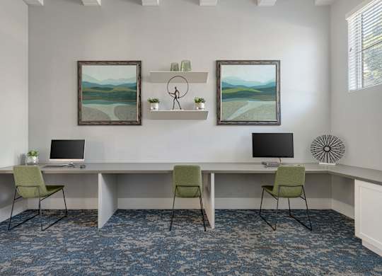 A room with a desk, chairs, and two paintings on the wall.