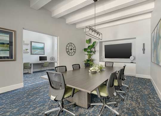 A conference room with a long table surrounded by chairs.