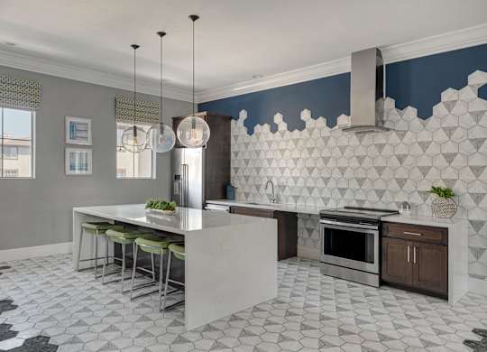 A kitchen with a white island and a black and white floor.