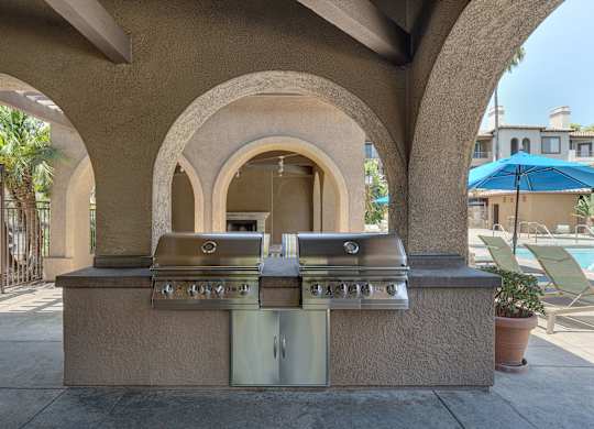 A barbecue grill is built into a wall with arches.