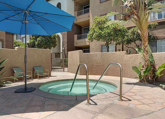 A blue umbrella is next to a pool in a courtyard.