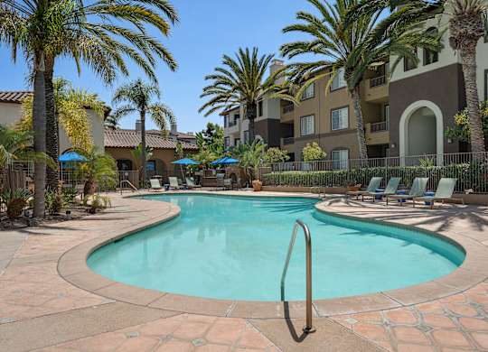 A swimming pool surrounded by palm trees and lounge chairs.