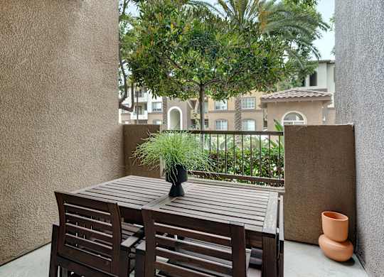 A table with chairs and a potted plant on a balcony.