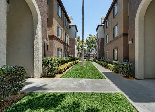 A long, narrow walkway separates two rows of apartment buildings.
