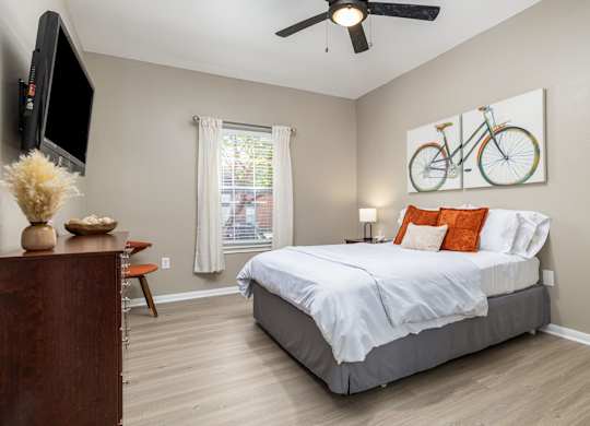 A bedroom with a large bed and a television on the wall at Clear Creek Meadows Apartments, Copperas Cove, 76522