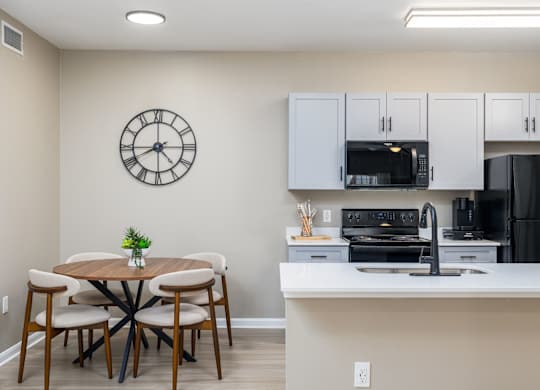 A kitchen with a table and chairs and a clock on the wall at Clear Creek Meadows Apartments, Copperas Cove
