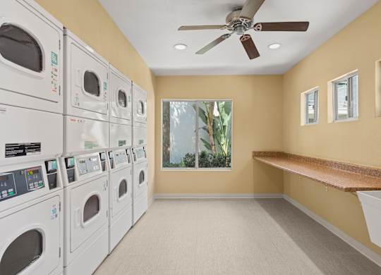 A laundry room with a row of washers and dryers.