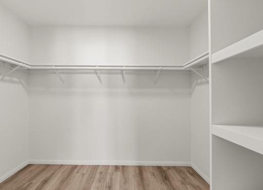 A spacious closet with hardwood floors and shelving.