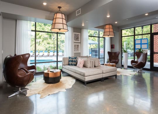 a living room with a couch and chairs and large windows