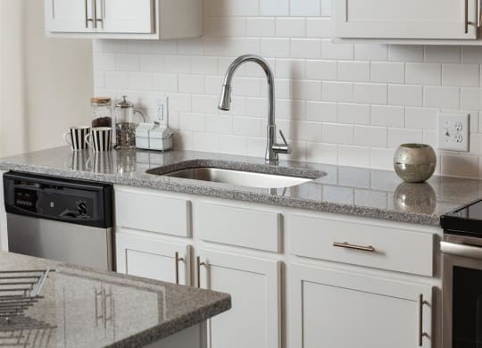 a white kitchen with granite counter tops and a sink