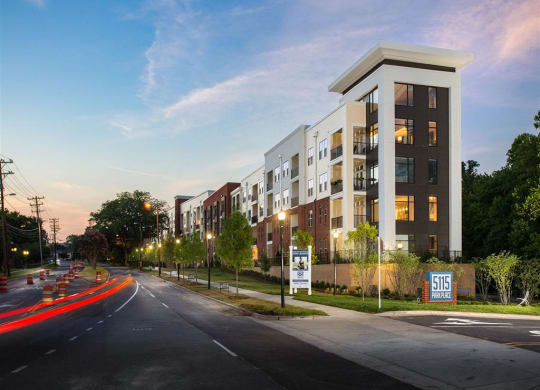 a rendering of an apartment building at dusk on a city street