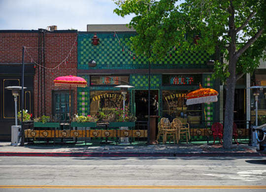 a street view of a restaurant with tables and umbrellas