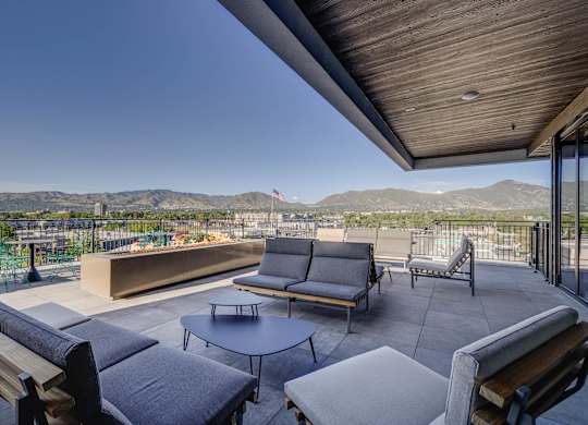 A patio with a table and chairs overlooking a mountain range.