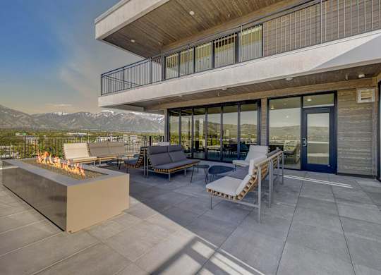 A modern patio with a fire pit and seating area.