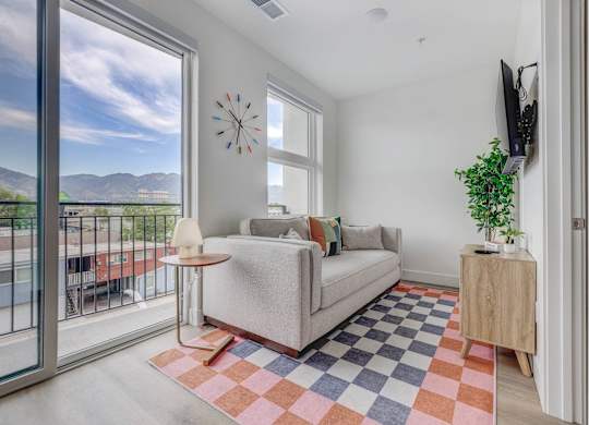 A living room with a couch, a table, a plant, and a TV.
