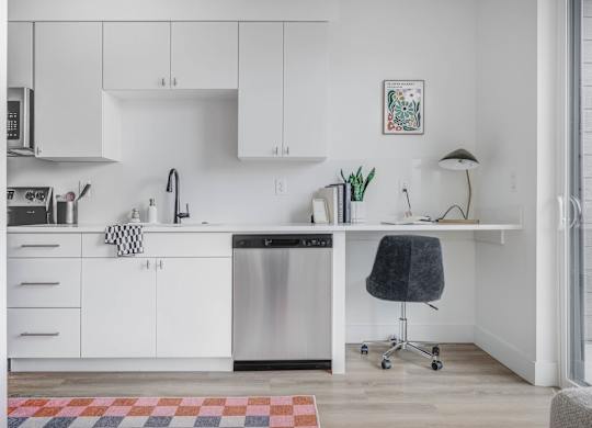 A kitchen with white cabinets and a black chair.