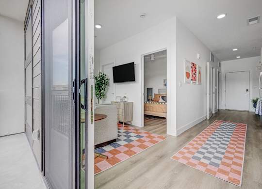 A modern living room with a white interior and a glass door leading to a balcony.